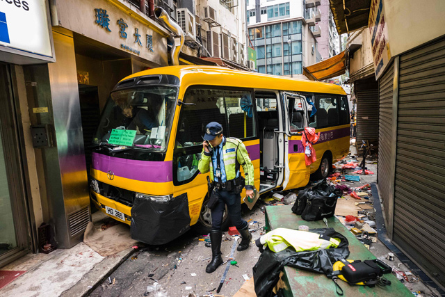Police investigate after an empty schoolbus crashed in the North Point district of Hong Kong on Monday (AFP photo)