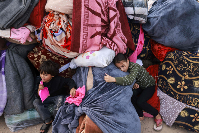Children rest on blankets as displaced Palestinians fleeing central and southern Gaza set up tents in the new Tall El Sultan camp west of Rafah in the southern Gaza Strip, on Sunday, amid continuing Israeli bombardment of the besieged territory  (AFP photo)