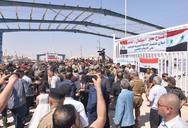 People and media flood the Syrian side of the border-crossing between Albu Kamal in Syria and Al Qaim in Iraq, on Monday, after the crossing reopened on Monday after it was seized by the Daesh terror group in 2014 (AFP photo)