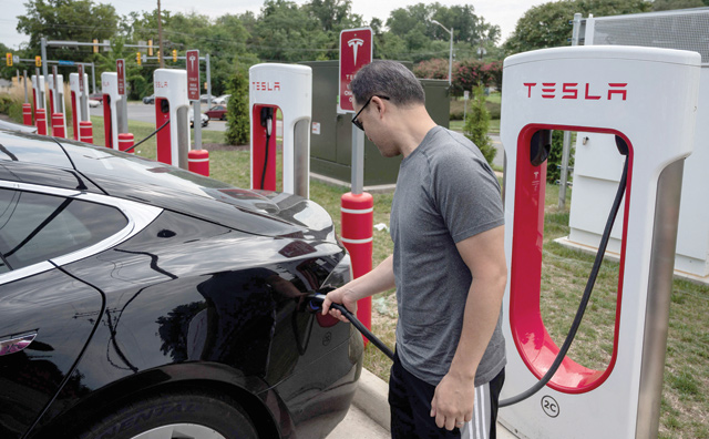 A man charges his car at a Tesla super charging station in Arlington, Virginia, on Friday (AFP photo)