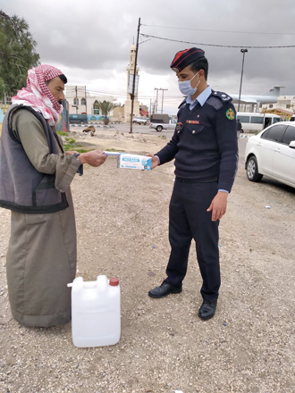 A police officer is seen distributing face mask to a man in Mafraq, some 80 kilometres northeast of Amman, on Thursday (Petra photo)