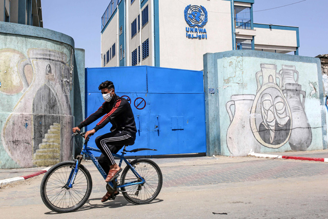 A Palestinian rides a bicycle past the closed gate of a school run by the United Nations Relief and Works Agency for Palestinian Refugees (UNRWA) in the city of Rafah in the southern Gaza Strip, on Tuesday, amidst a lockdown due to the COVID-19 coronavirus pandemic (AFP photo)