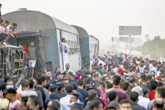 People gather by an overturned train carriage at the scene of a railway accident in the city of Toukh in Egypt's central Nile Delta province of Qalyubiya on April 18 (AFP photo)