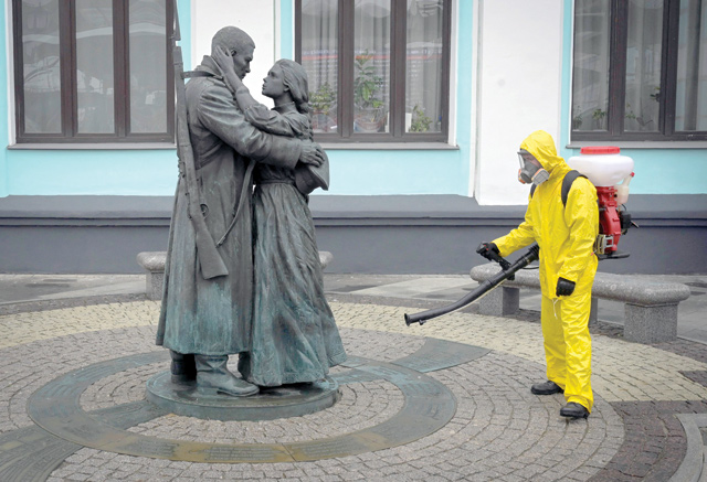 A serviceman of the Russian Ministry for Civil Defence, Emergencies and Elimination of Consequences of Natural Disasters, wearing protective gear, disinfects Moscow's Belorussky railway station next to a statue on Friday, amid the COVID-19 pandemic (AFP photo)