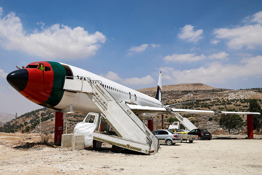 Palestinian twin brothers Atallah and Khamis Al Sairafi, 60, pose from the cockpit of a Boeing 707 aircraft being converted into a restaurant they are calling 'The Palestinian-Jordanian Airline Restaurant and Coffee Shop Al Sairafi Nablus', in the city of Nablus in the occupied West Bank on July 5 (AFP photo)