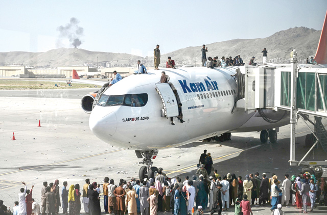 Afghan people climb atop a plane as they wait at the Kabul airport in Kabul on Monday, after a stunningly swift end to Afghanistan's 20-year war, as thousands of people mobbed the city's airport trying to flee the group's feared hardline brand of Islamist rule (AFP photo)