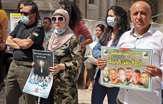 People gather with signs for a demonstration in support of Palestinian prisoners held in Israeli prisons, outside the ICRC offices in Ramallah in the occupied West Bank, on Tuesday (AFP photo)