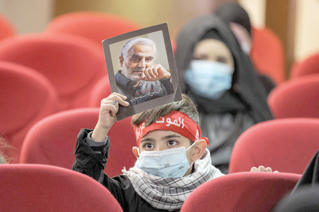 A boy holds up a sign showing the portrait of Qasem Soleimani, the slain top commander of the Iranian revolutionary guard corps, during a memorial service marking the second anniversary of his death alongside Iraqi commander Abu Mahdi Al Muhandis in a US raid, at a hall in a school in the southern suburb of Lebanon's capital Beirut on Monday (AFP photo)