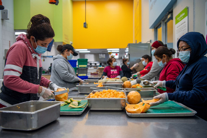 Community volunteers cut and prepare fruit at the Houston Food Bank facility on Tuesday in Houston, Texas. Prices for produce continue to rise as labour shortages, transportation problems, import challenges and supply chain difficulties stress food banks and produce distribution centres around the country (AFP photo)