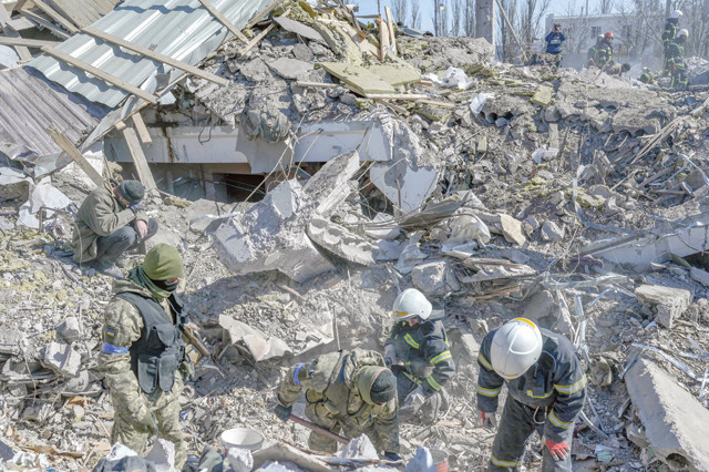 Ukrainian soldiers and rescue officers search for bodies in the debris at the military school hit by Russian rockets the day before, in Mykolaiv, southern Ukraine, on Saturday (AFP photo)