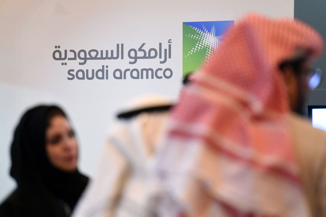 In this file photo taken on January 25, 2016, Saudi and Foreign investors stand in front of the logo of Saudi state oil giant Aramco during the 10th Global Competitiveness Forum (AFP photo)
