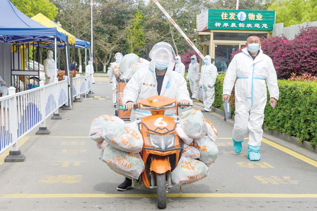 A delivery man wearing personal protective equipment prepares to deliver food bought online for residents who were restricted due to a recent COVID-19 coronavirus outbreak, in Ningbo in China's eastern Zhejiang province, on Saturday (AFP photo)