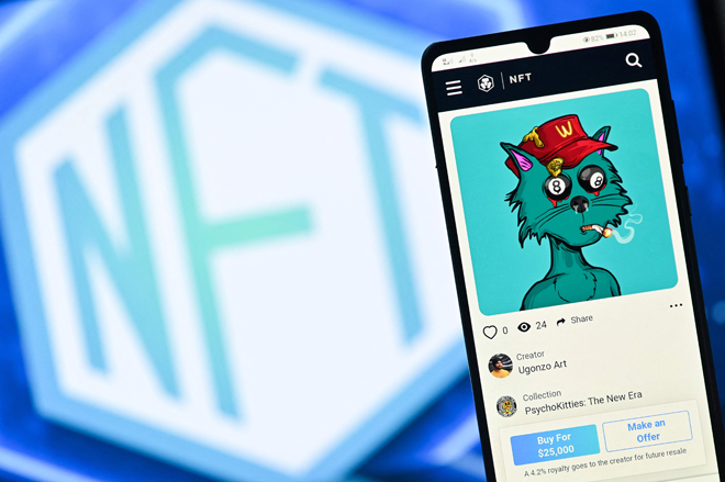 This file illustration photo taken in London on December 30, 2021 shows a PsychoKitty NFT (Non-Fungible Token) created by psychedelic artist Ugonzo displayed on a phone and a NFT logo displayed on a computer screen from a Crypto.com NFT marketplace (AFP photo)