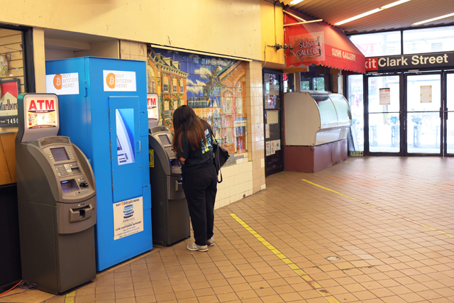 A person uses an ATM machine next to a Bitcoin ATM at the Clark Street subway station on Monday in the Brooklyn Heights neighborhood of Brooklyn in New York City (AFP photo)