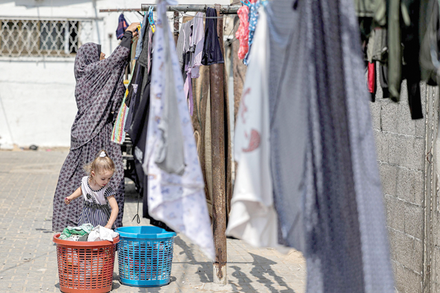 A girl assists a woman as she hangs freshly-washed clothes to dry in her home in the Jabalia camp for Palestinian refugees in the north of the Gaza Strip on Sunday (AFP photo)