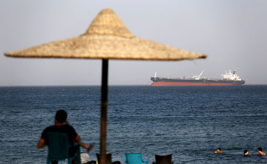 People enjoy at the beach in El Ain El Sokhna port in front of an Egyptian crude oil tanker ‘Sharifa 4’ in Suez before it enters the Suez Canal, east of Cairo, on Sunday (Reuters photo)