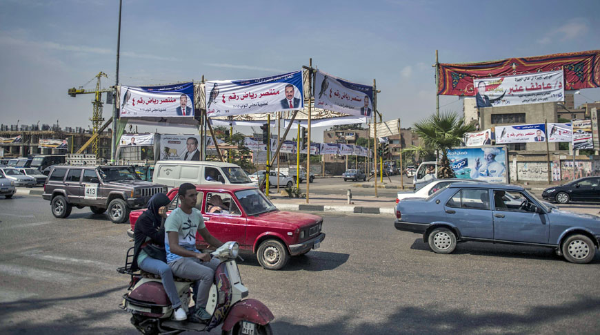 Egyptians drive past banners advertising candidates for the upcoming parliamentary elections in the Giza district of the capital Cairo on Monday (AFP photo)