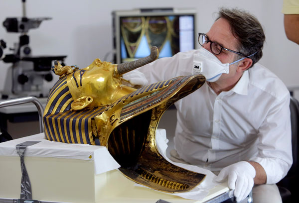 German restorer Christian Eckmann examines the beard of the golden mask of the famed King Tutankhamun as an Egyptian-German team begins restoration work over a year after the beard was accidentally broken off and hastily glued back with epoxy, at the Egyptian Museum in Cairo, Egypt, on Tuesday (AP photo)