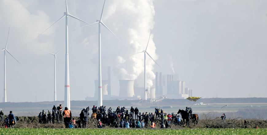 Policemen and activists are seen at the edge of the Garzweiler lignite mine during a demonstration in Keyenberg, western Germany, as protests continue against a coal mine extension in the nearby village of Luetzerath, on Tuesday; German energy supplier RWE's coal fired power plant of Neurath is seen in the background (AFP photo)