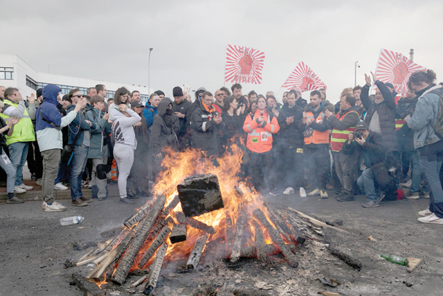 Striking employees gather around a fire outside Gronfreville-l'Orcher refinery on Friday, during a demonstration a week after the government pushed a pensions reform through parliament without a vote, using Article 49.3 of the constitution (AFP photo)