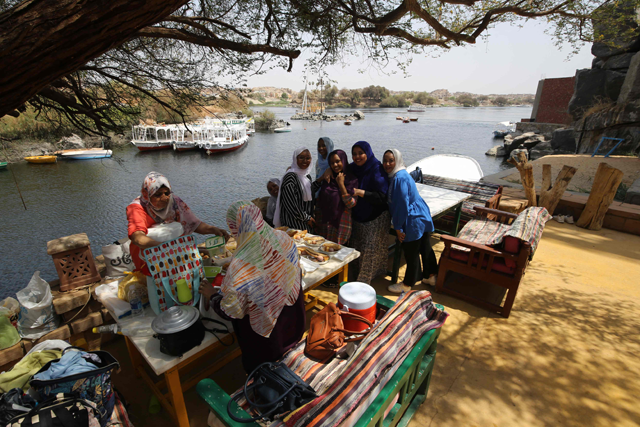 Sudanese women who fled the war in their country share a meal on the banks of the Nile River in the Egyptian city of Aswan, on Friday (AFP photo)