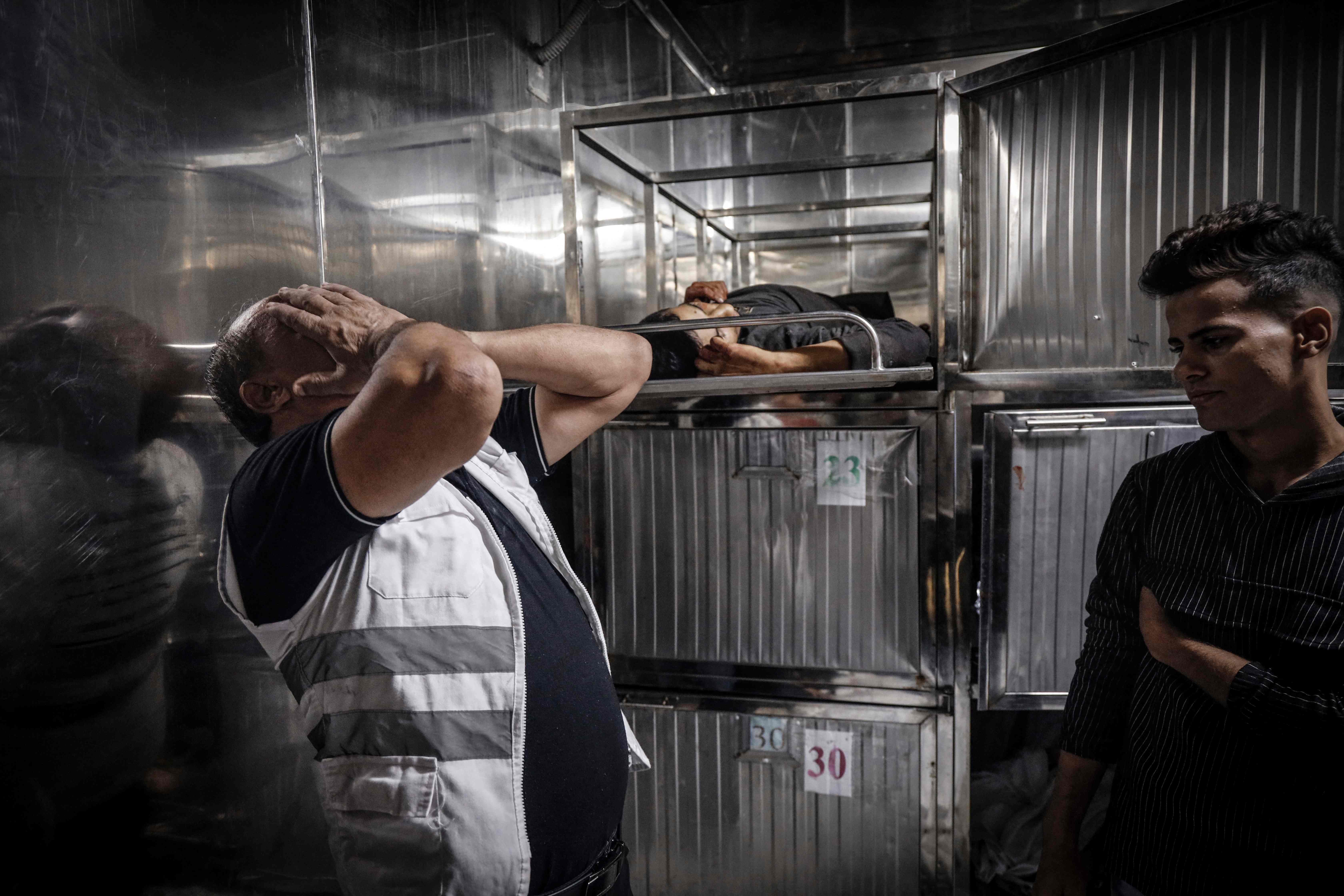  A man weeps next to the body of one of the Palestinian fighters killed at the mortuary of a hospital in Gaza City on Saturday (AFP photo by Eyad Baba)