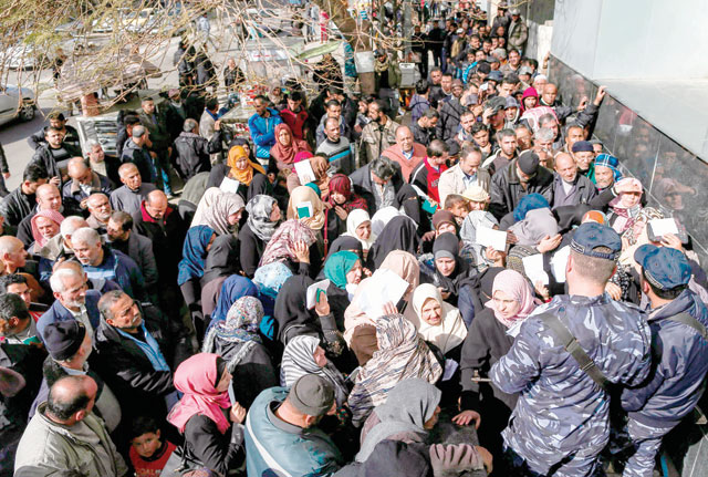 Security forces loyal to Hamas organise people crowding as they queue outside the central post office in Gaza City on Saturday to receive financial aid from the Qatari government given to impoverished Palestinian families (AFP photo)
