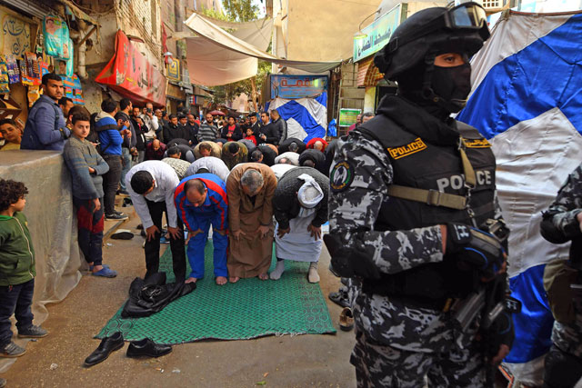 A member of the Egyptian special forces stands guard as people pray outside a mosque during the funeral of policeman Mahmoud Abu El Yzied, one of three policemen killed in a bombing a day earlier, in the Embaba district of the capital Cairo, on Tuesday (AFP photo)