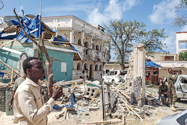   A man passes in front of the rubbles of the popular Medina hotel of Kismayo on Saturday, a day after at least 26 people, including several foreigners, were killed and 56 injured in a suicide bomb and gun attack claimed by Al Shabaab militants (AFP photo)