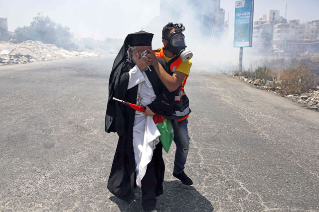   A clergyman reacts to tear gas fired by Israeli forces during a protest against a US-sponsored Middle East economic conference in Bahrain, on Tuesday, in the West Bank city of Ramallah (AFP photo)