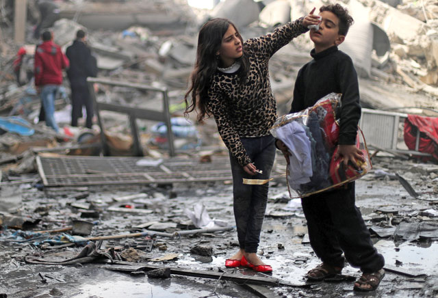 A Palestinian girl cleans the face of her brother outside their destroyed house after an Israeli missile targeted a nearby Hamas site, in Gaza City, on Tuesday (Reuters photo)