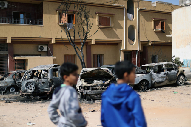 Two Libyan boys look at vehicles damaged by an overnight shelling in Abu Salim district in Tripoli, Libya, on Wednesday  (Reuters photo)