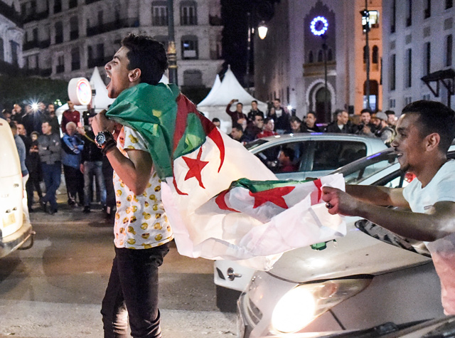 Algerian youths march with national flags during a demonstration in the centre of the capital Algiers on Monday, after President Abdelaziz Bouteflika announced his withdrawal from a bid to win another term in office and postponed an April 18 election, following weeks of protests against his candidacy  (AFP photo)