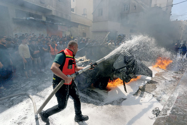 A member of Palestinian Civil Defence extinguishes a fire in the car of a Hamas commander who was killed in an Israeli air strike, in Gaza City, on Sunday (Reuters photo)
