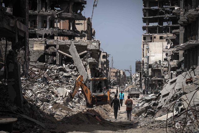 People walk on a road lined with destroyed buildings in Khan Yunis in the southern Gaza Strip on Tuesday (AFP photo)