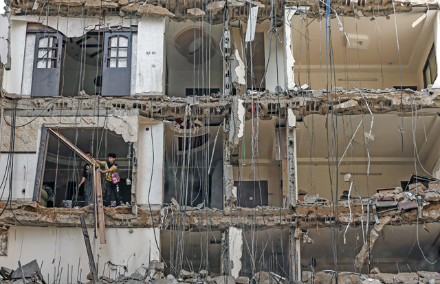Palestinians clear rubble in a building damaged by an Israeli air strike earlier this week in the Gaza Strip on Wednesday (AFP photo)