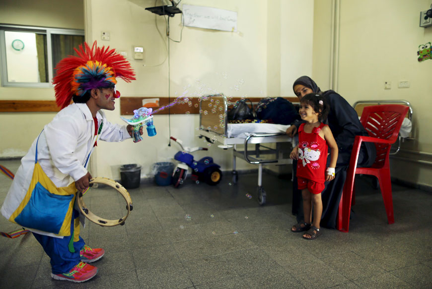 A Palestinian social activist working for the International South South Cooperation (Cooperazsione Internazionale Sud Sud, or CISS) entertains a child who is a cancer patient, inside a hospital in Gaza City on Monday. Activists working for the Italian nonprofit NGO use entertainment and humour to help bring treatment to children suffering from psychological trauma in the Gaza Strip (Reuters photo)