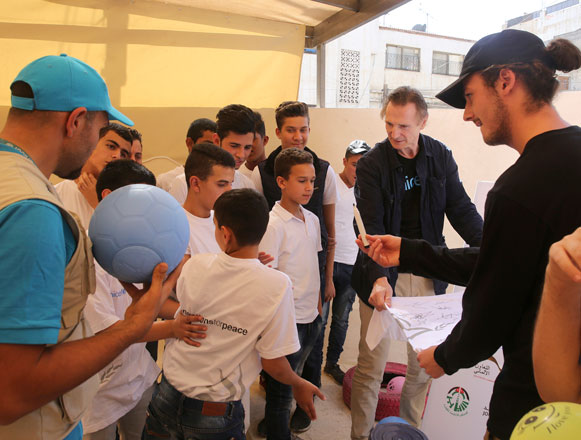 Actor Liam Neeson listens to stories from Syrian and Jordanian students at a community centre in Amman on Tuesday (AP photo)