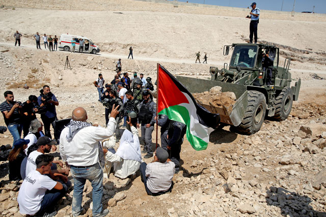 Palestinians gather in front of an Israeli bulldozer as they protest against Israel's plan to demolish the Palestinian Bedouin village of Khan Al Ahmar in the occupied West Bank on September 14 (Reuters file photo)