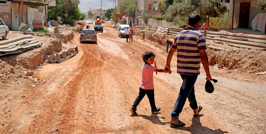 A father and his daughter cross a street under renovations as part of a USAID grant in the village of Al Badhan, north of Nablus in the occupied West Bank, on Saturday (AFP photo)