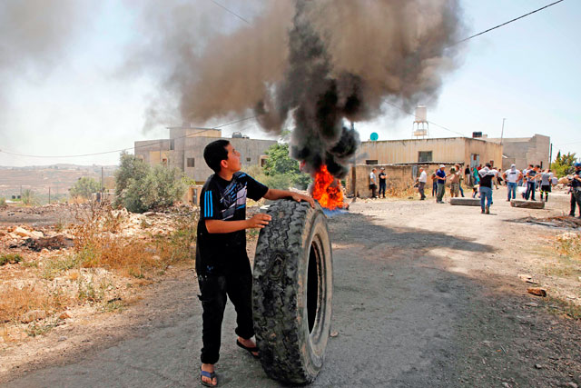   A Palestinian protester rolls a tyre during a demonstration against the US-led Palestinian-Israeli peace conference in Bahrain, in the village of Kfar Qaddum, near Nablus in the occupied West Bank, on Friday (AFP photo)