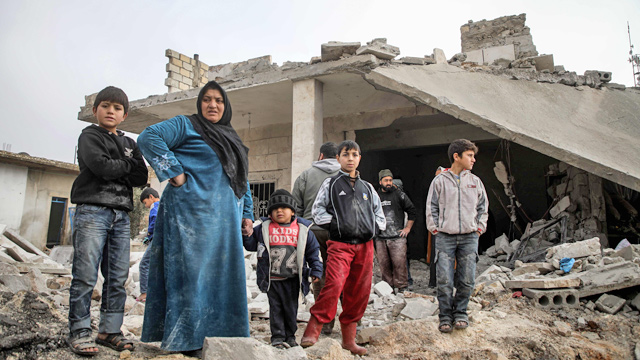 Syrians stand in a street next to debris and rubble from buildings which were damaged by reported air strikes in the rebel-held town of Orum Al Kubra, in the northern Syrian province of Aleppo, on Saturday (AFP photo)