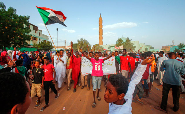 Sudanese people chant slogans and wave national flags as they celebrate after protest leaders struck a deal with the ruling generals on a new governing body, in the capital Khartoum's eastern district of Burri, on Friday (AFP photo)