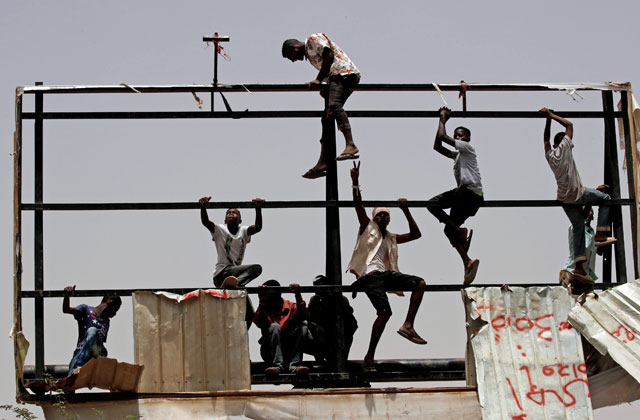   Protesters climb an old billboard frame during a demonstration in front of the Defence Ministry in Khartoum, Sudan, on Thursday (Reuters photo)