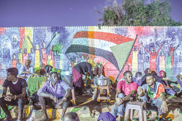 In this file photo taken on April 24, Sudanese protesters sit in front of a recently painted mural during a demonstration near the army headquarters in the capital Khartoum (AFP photo)