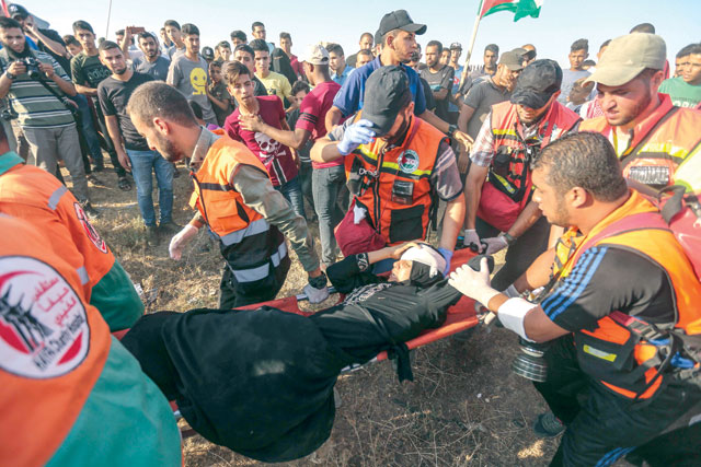 Palestinian paramedics carry a wounded protester during confrontations with Israeli forces near the fence along the border with Israel in the eastern Gaza Strip on Friday (AFP photo) 