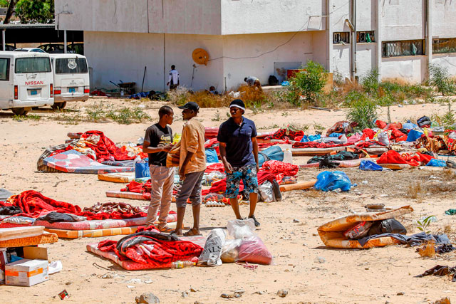 Migrants stand and walk outside at a detention centre used by the Libyan Government of National Accord in the capital Tripoli's southern suburb of Tajoura on Wednesday, following an air strike on a nearby building that left dozens killed the previous night (AFP photo)