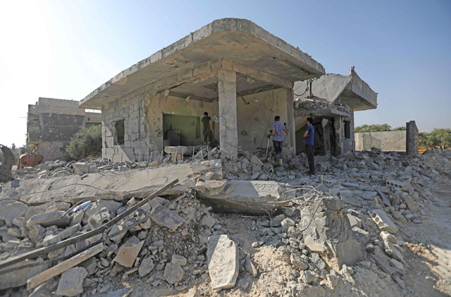 Syrians check the damage in an area targeted by reported air strikes by pro-government forces in the town of Binnish in Idlib province on Monday (AFP photo)