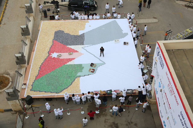 Employees and students at the Royal Academy of Culinary Arts work on a mosaic painting of cakes in celebration of Jordan’s 70th Independence Day on Wednesday (Photo courtesy of RACA)