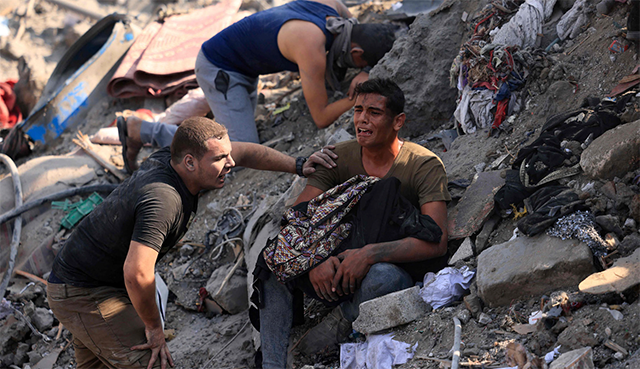 A man reacts as he holds the remains of his mother wrapped in a blanket amid the rubble of building destroyed in an Israeli strike on the Bureij refugee camp in the central Gaza Strip on Thursday (AFP photo)
